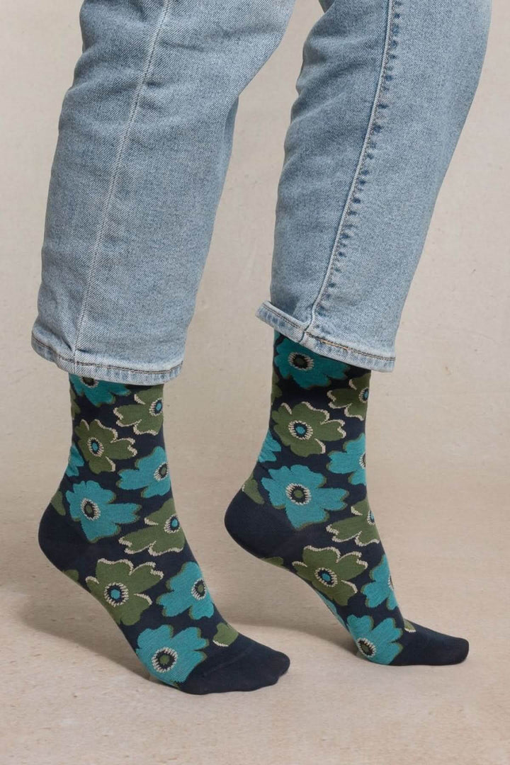 Chaussettes à motif floral en coton, mi-mollet, avec imprimé vibrant, portées avec un jean retroussé pour un style original et frais.