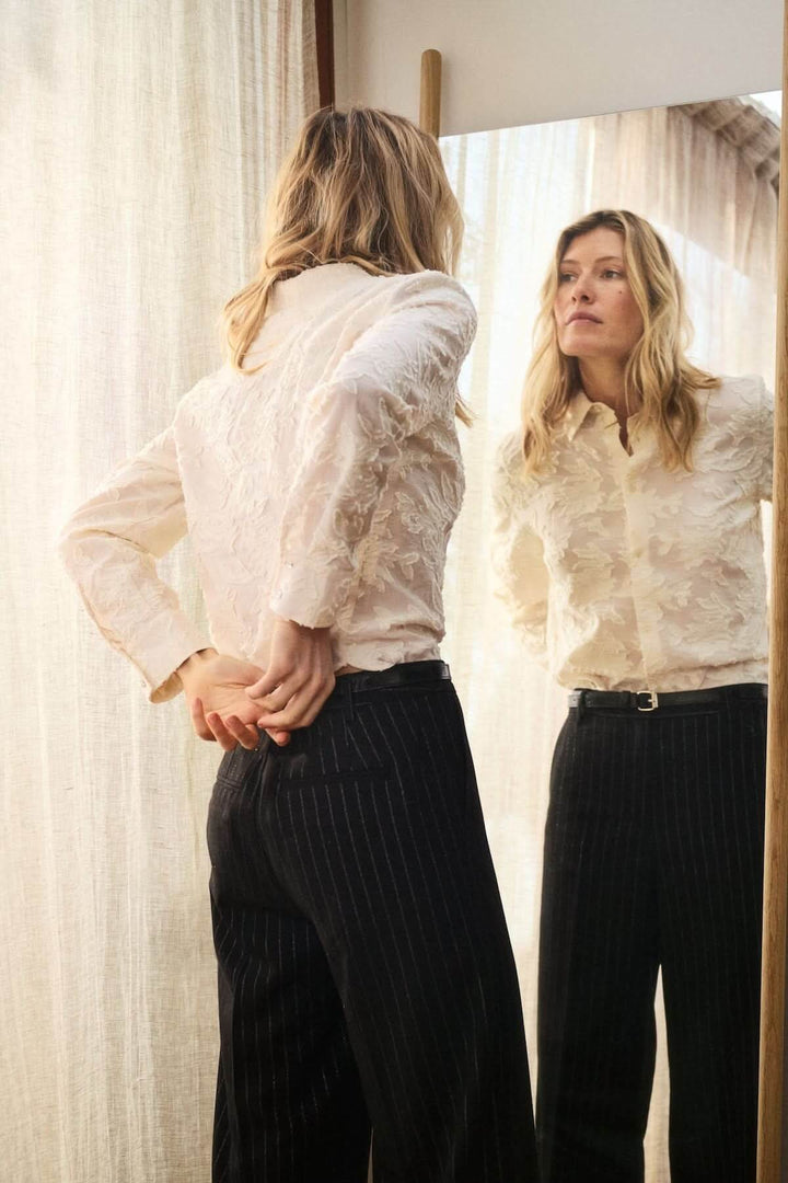 Chemise Vilya à relief floral ton sur ton en viscose LENZING™ ECOVERO™, élégante et raffinée, vue de dos devant un miroir.