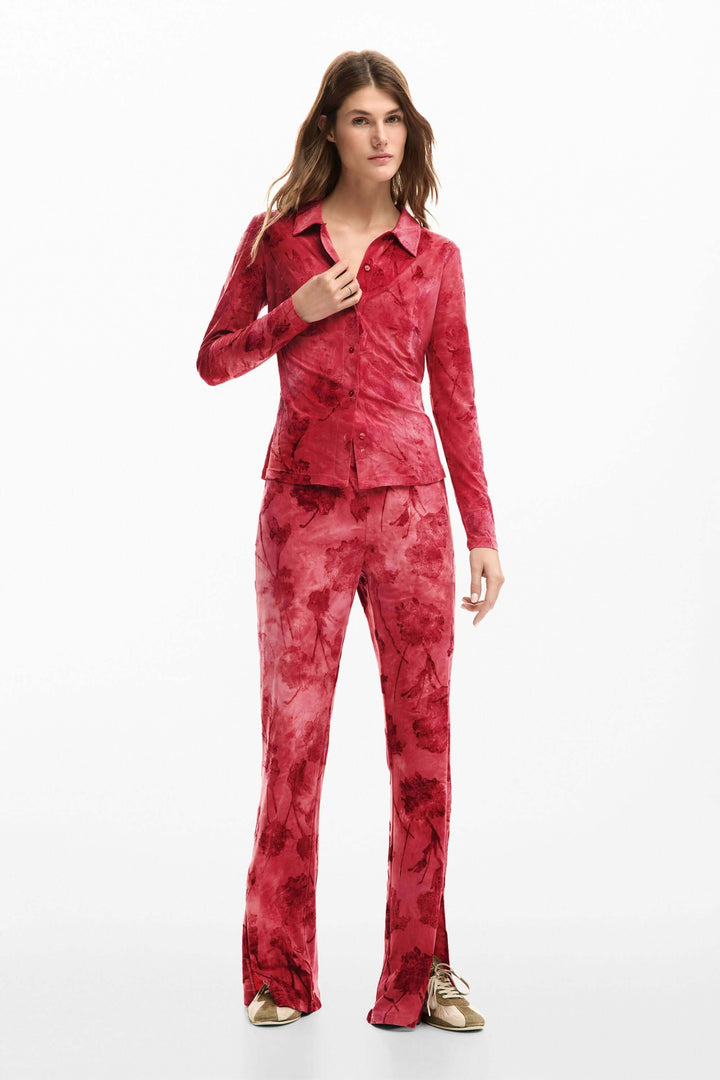Femme portant une chemise brodée avec fleurs, rouge, à manches longues, style ajusté, avec un pantalon assorti.