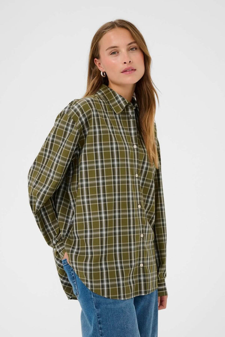Femme portant une chemise à carreaux verte et blanche, style décontracté et intemporel, pour un look casual chic.