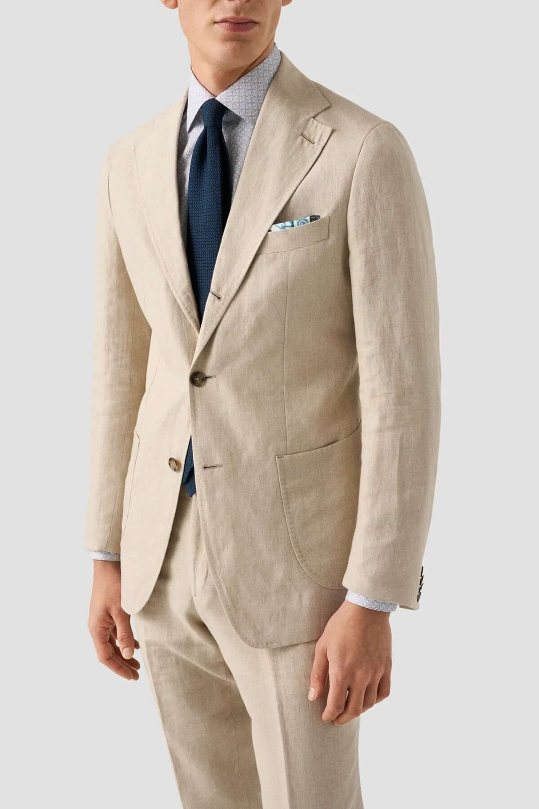 Homme en costume beige élégant, chemise à motifs et cravate, style professionnel et raffiné.