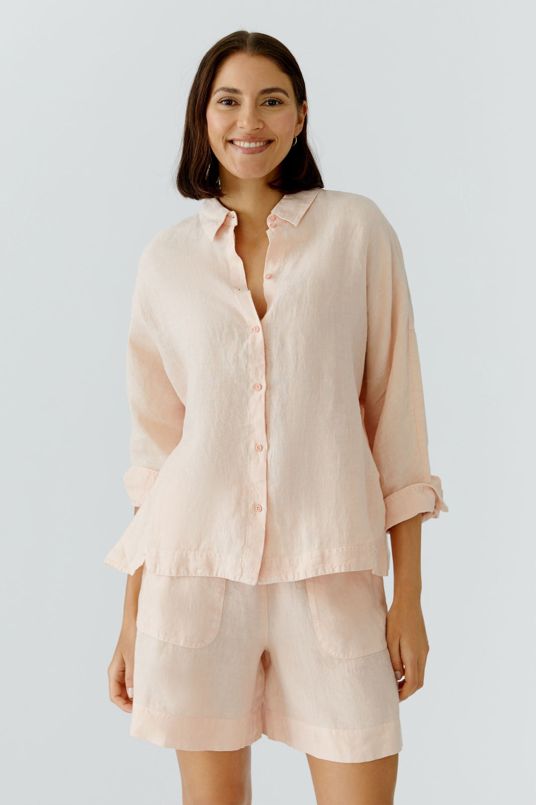 Femme portant une chemise fluide à manches longues, couleur pastel, avec un col classique et une fermeture boutonnée, style élégant et décontracté.