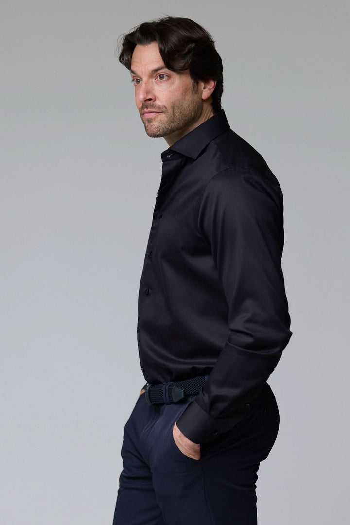 Homme portant une chemise infroissable de base satinée noire, coupe ajustée élégante, pour un look sophistiqué et professionnel.