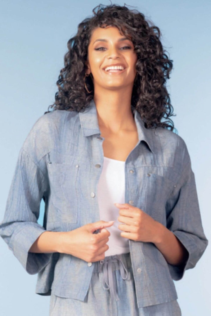 Chemise légère à poches plaquées avec manches trois-quarts, portée ouverte sur un haut blanc, pour un style décontracté et moderne.