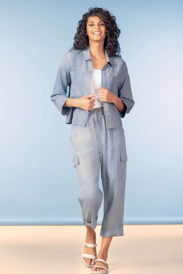 Modèle portant une chemise légère à poches plaquées avec manches trois-quarts, style décontracté et moderne, sur fond bleu.