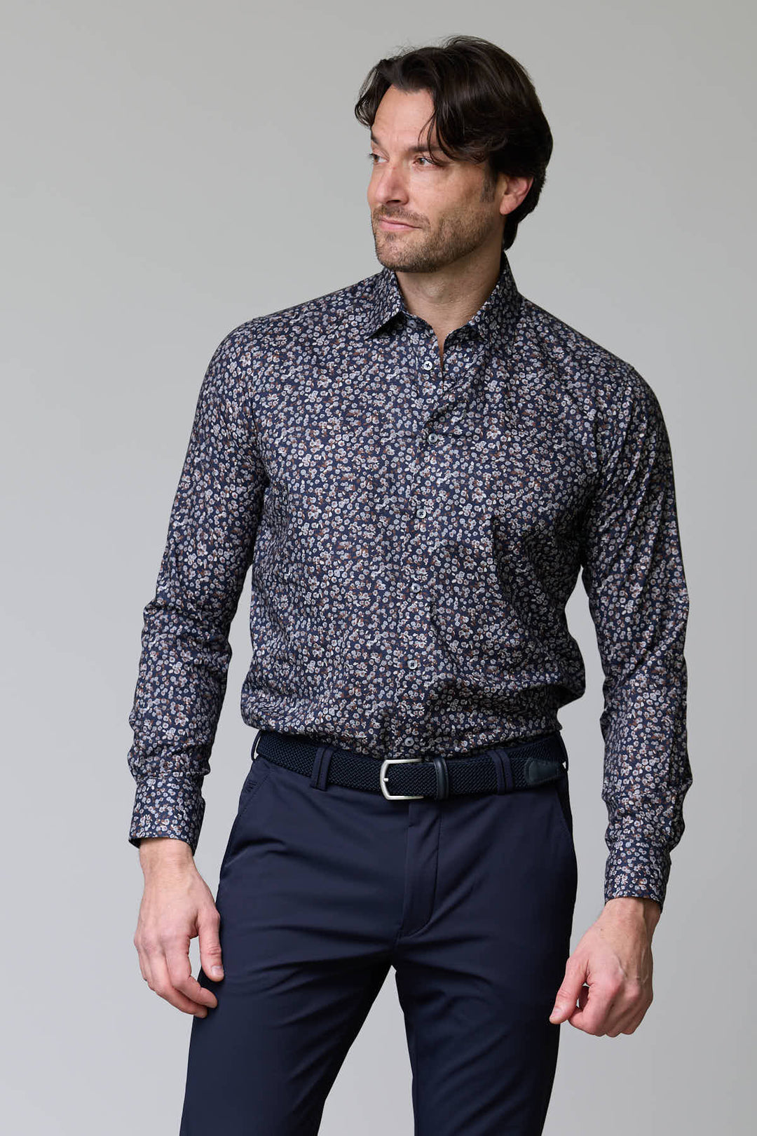 Homme portant une chemise à motif floral abstrait avec pantalons sombres, style élégant et moderne, col classique, boutons finis nacré.