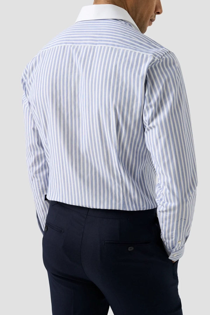 Homme portant une chemise à rayures Bengal à col blanc avec un pantalon foncé.