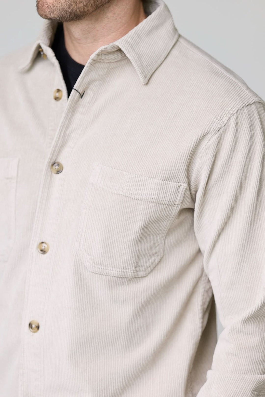 Homme portant une chemise sport en velours côtelé style surchemise, beige, avec des poches plaquées et boutons contrastants.