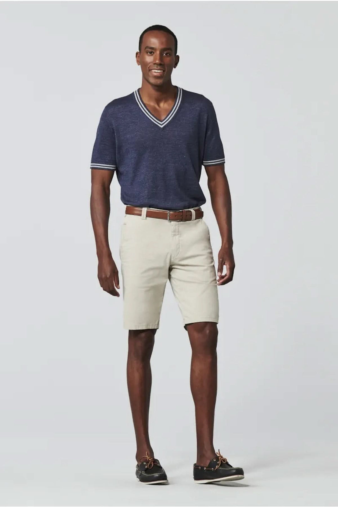 Homme souriant portant un t-shirt bleu marine et un short chino beige pour un look estival élégant.