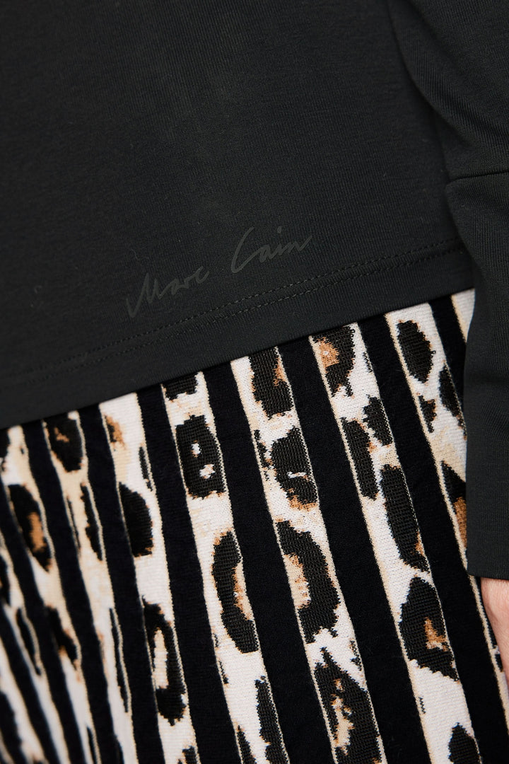 Col roulé ajusté noir avec jupe plissée imprimée animal, détail élégant et moderne, style chic parfait pour look affirmé.