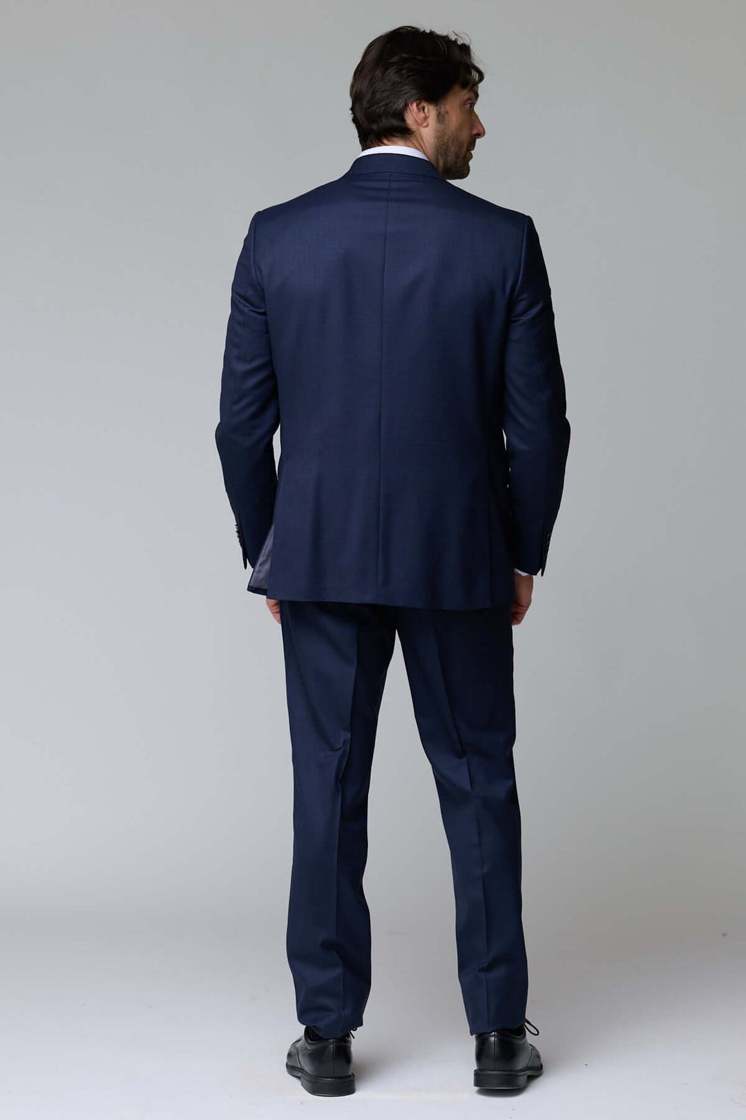 Homme portant un complet classique deux pièces bleu, vu de dos, idéal pour le bureau et les événements formels.