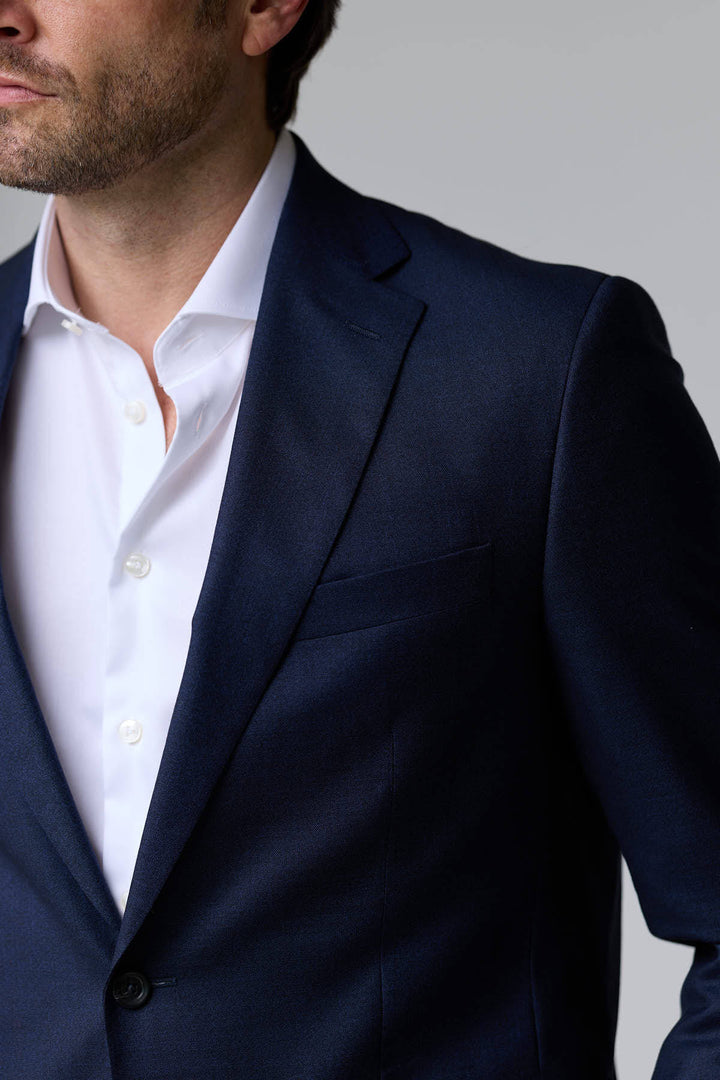 Homme portant un complet classique deux pièces bleu marine, élégant et ajusté, parfait pour le bureau et les occasions formelles.