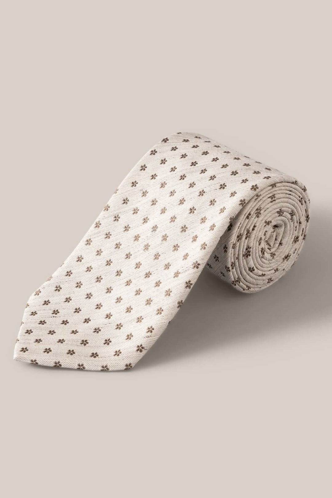 Cravate en lin et soie beige avec motif floral subtil en brun, élégante pour occasions habillées.