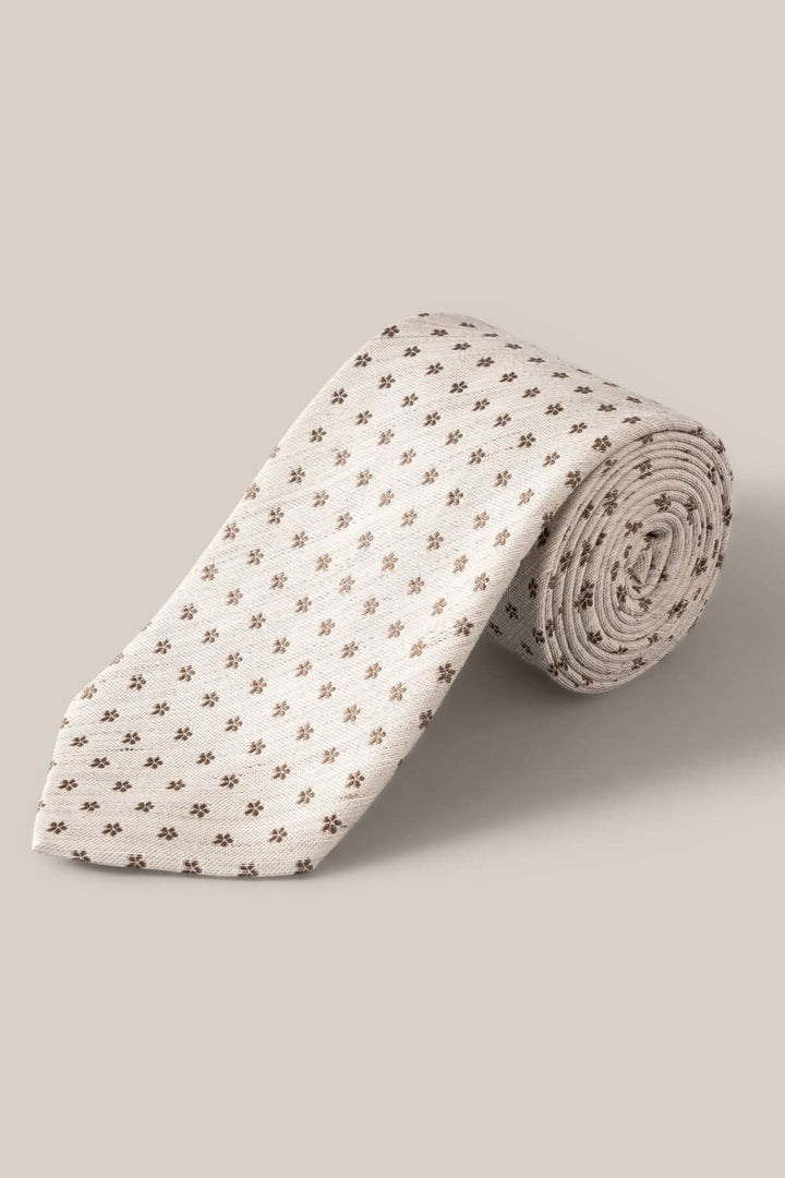 Cravate en lin et soie beige avec motif floral subtil en brun, élégante pour occasions habillées.