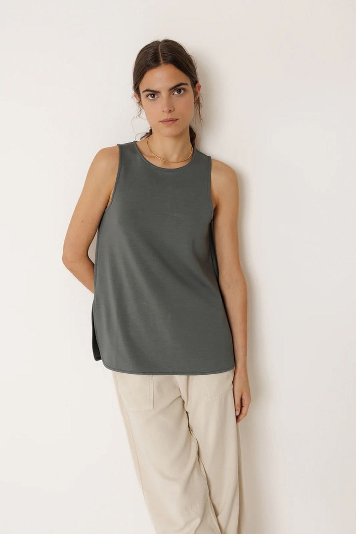 Femme portant un débardeur minimaliste à coupe fluide gris avec pantalon beige, style moderne et épuré.