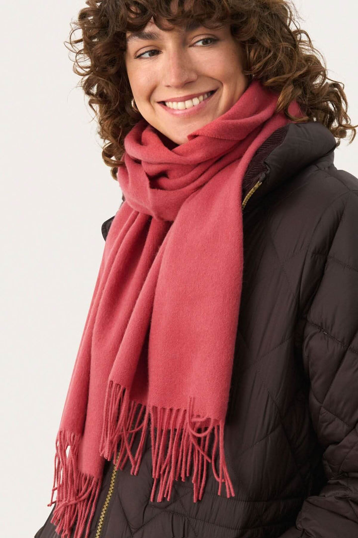 Foulard en laine Kitha en couleur rose porté par une femme souriante, parfait pour l&
