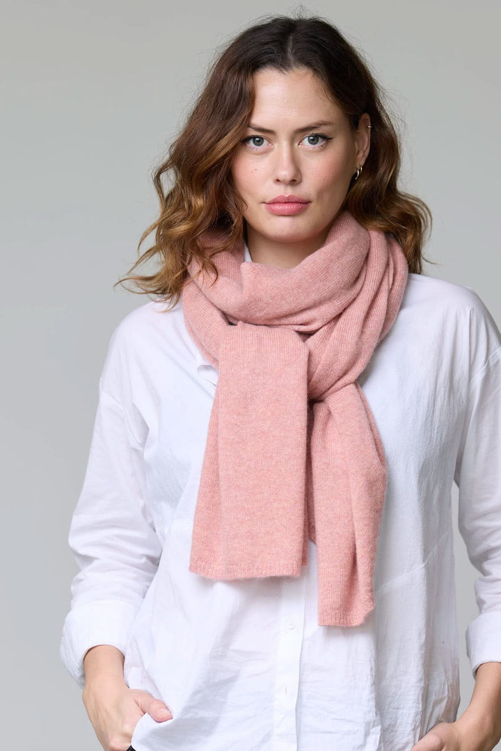 Femme portant un foulard en laine doux et raffiné rose, idéal pour les tenues automnales et hivernales, offrant chaleur et élégance.