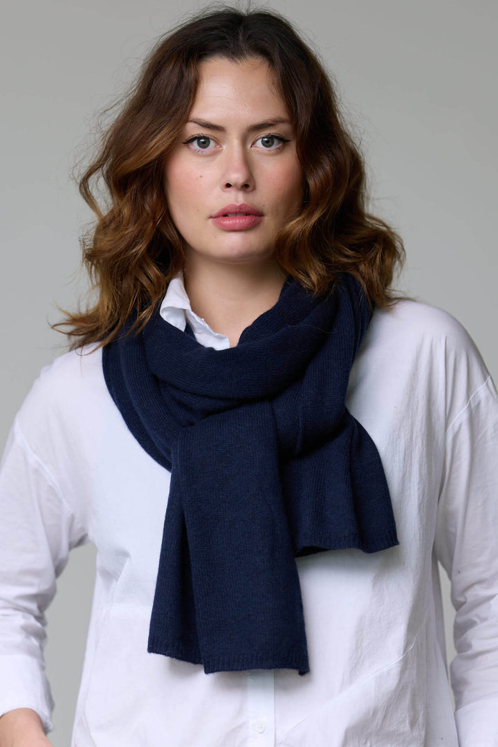 Foulard en laine bleu marine porté par une femme, texture moelleuse et enveloppante, parfait pour les saisons froides, détaillé et élégant.