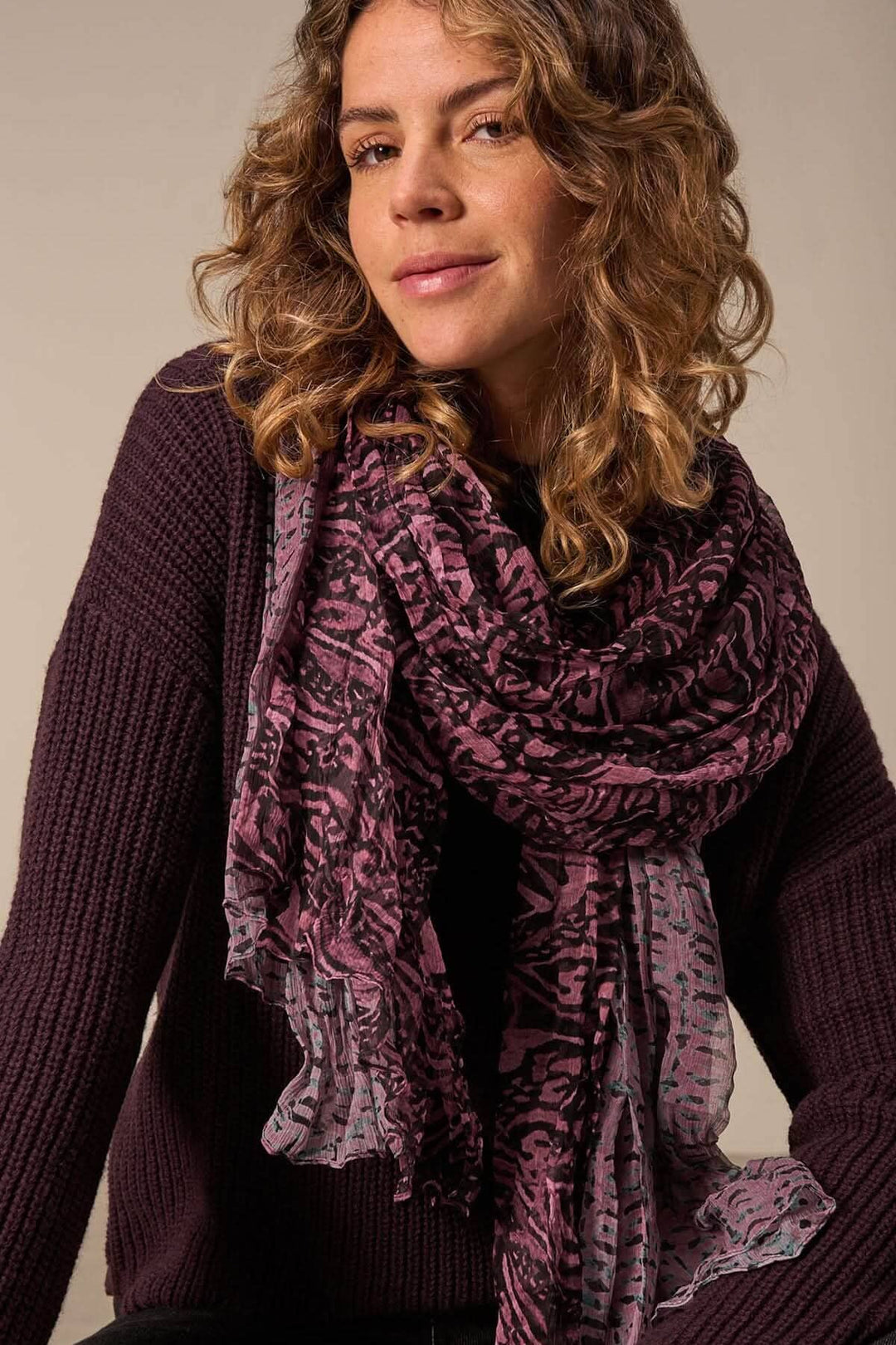 Foulard paréo en soie avec imprimé intégral, porté par une femme aux cheveux bouclés, ajoutant une touche d&