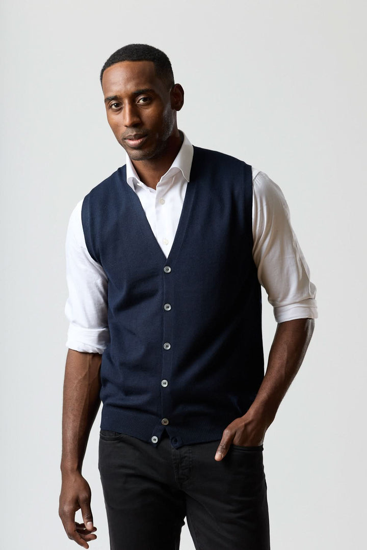 Homme portant un gilet en laine mérinos à col en V, élégant et ajusté, sur une chemise blanche pour un look raffiné.