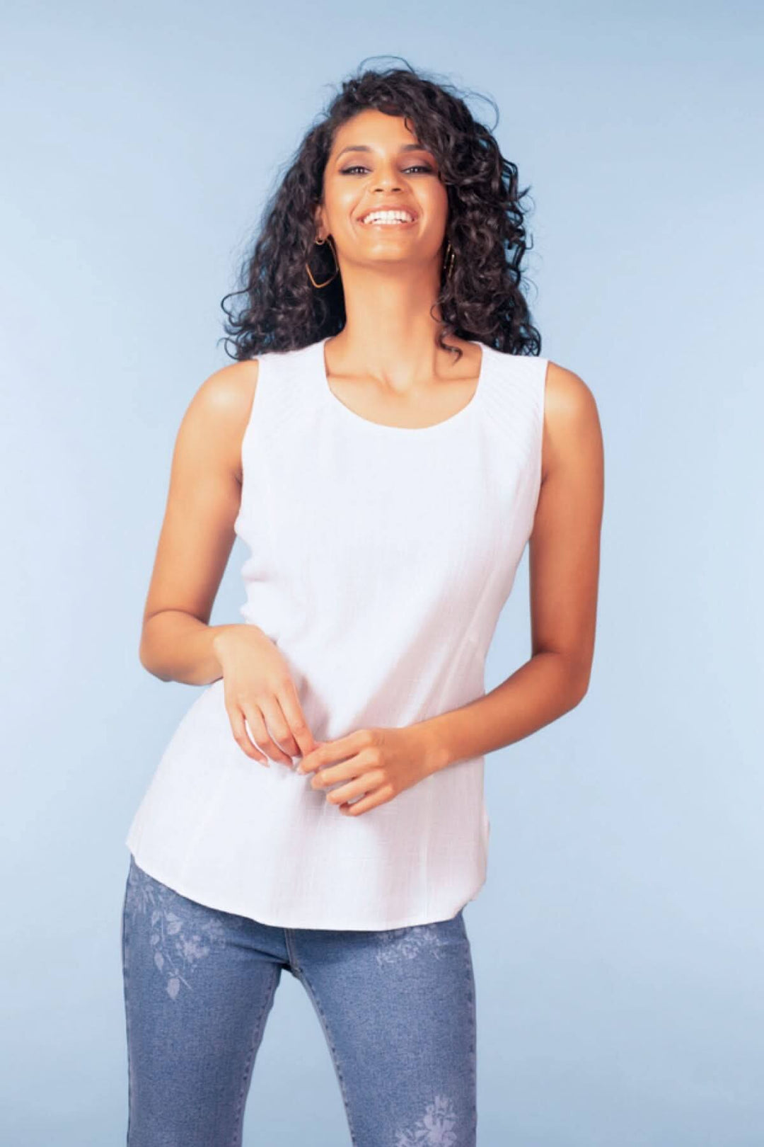 Femme portant un haut sans manches encolure ronde blanc, style épuré et coupe fluide pour un look soigné et polyvalent.