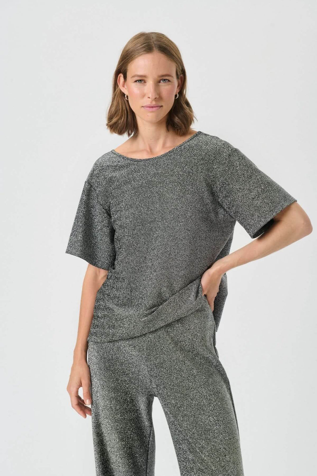 Femme portant le haut scintillant à dos dégagé Verrona avec manches courtes et encolure ronde.