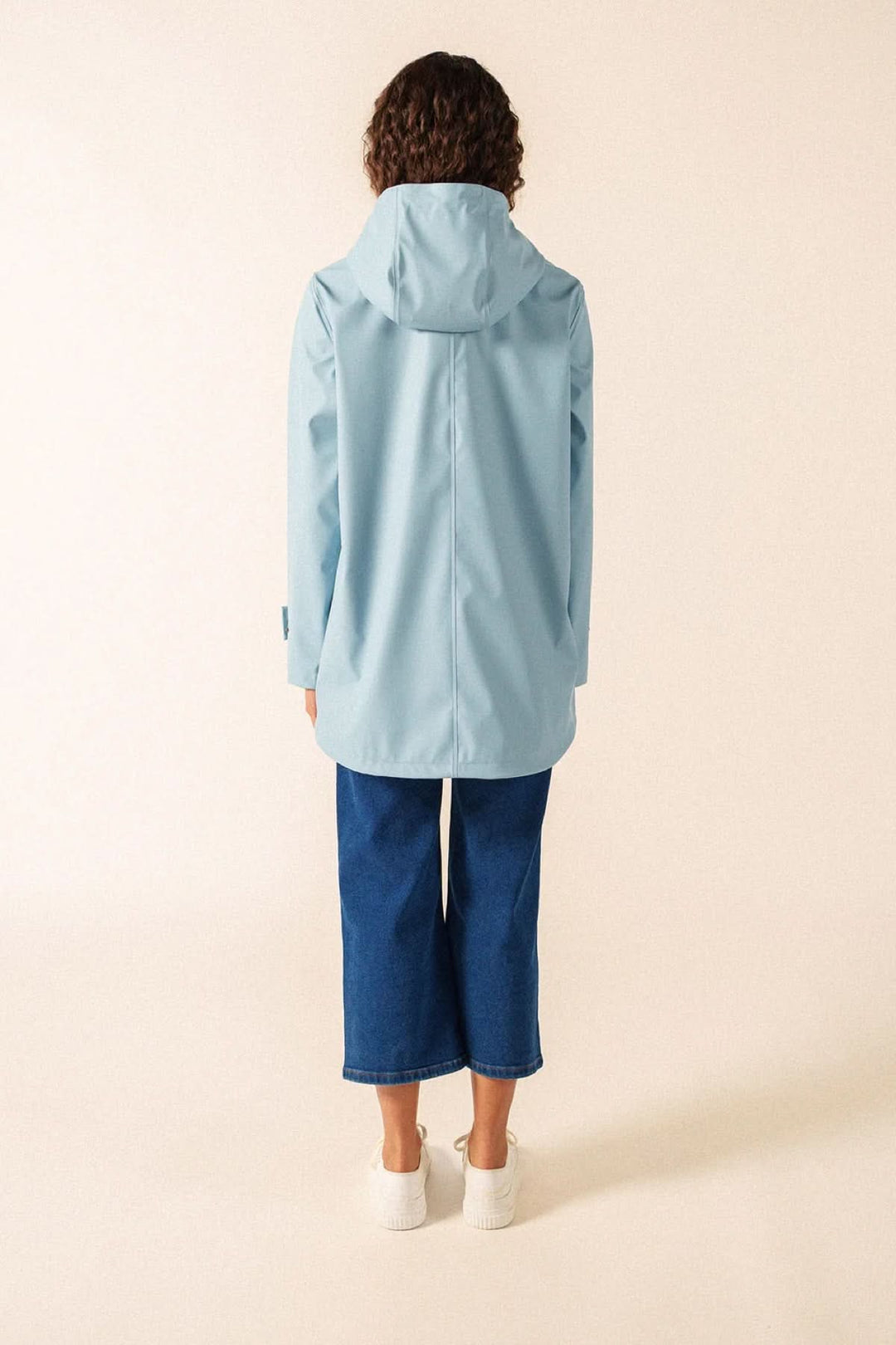 Femme portant un imperméable bleu clair Imperméable STE GAIA, ciré waterproof avec coutures soudées, idéal pour printemps et météo changeante.