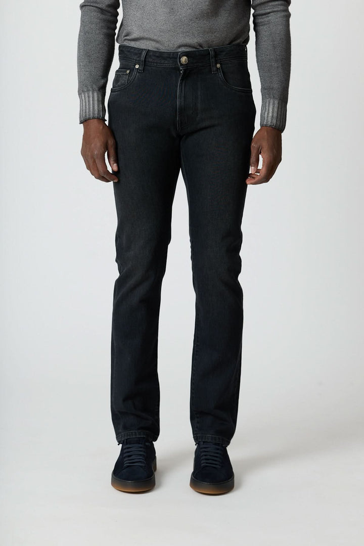 Jean 5 poches en denim stretch gris foncé ajusté, confort et style moderne, porté avec un pull à col roulé et sneakers.