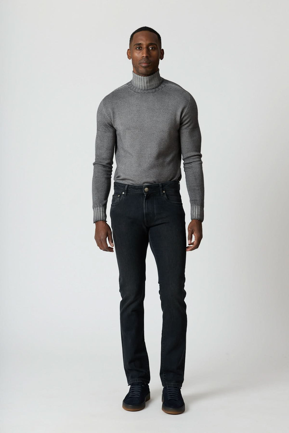 Homme portant un Jean 5 poches en denim stretch gris foncé avec col roulé gris et sneakers noires, style moderne et ajusté.