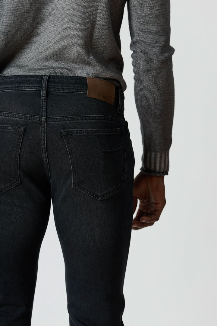 Jean 5 poches en denim stretch gris foncé avec silhouette ajustée, vue arrière, porté avec pull gris.