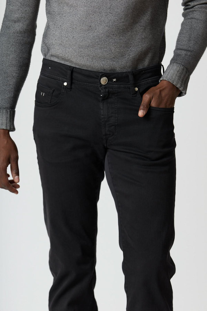 Jean 5 poches stretch coupe moderne noir avec taille moyenne, porté avec un pull gris, illustrant une coupe fuselée et confortable.