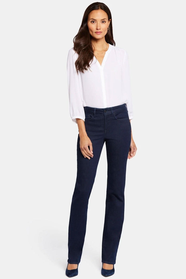 Femme portant le jean droit Marilyn avec chemisier blanc, montrant une silhouette élancée et classique.