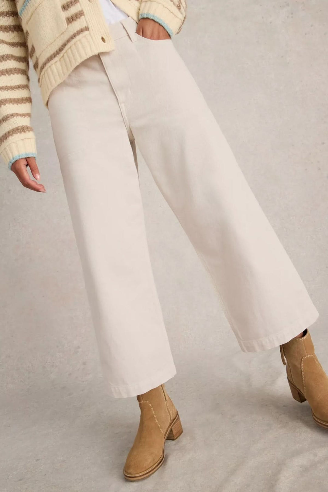 Jean Tia court à jambes larges, pantalon à taille haute et coupe droite en tissu clair, porté avec bottines marron et pull rayé.