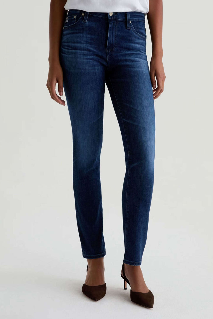 Jean ajusté à taille mi-haute en denim extensible, élégant et polyvalent, porté avec des talons pour un look décontracté-chic.