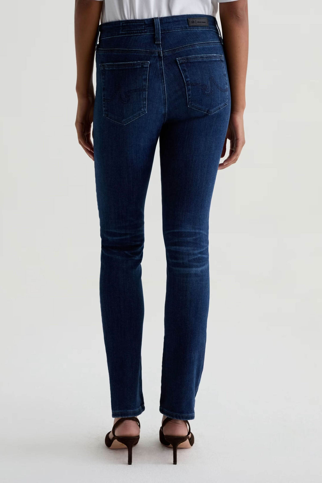 Jean ajusté à taille mi-haute, denim extensible, coupe ajustée, vue arrière, style décontracté-chic avec talons hauts.