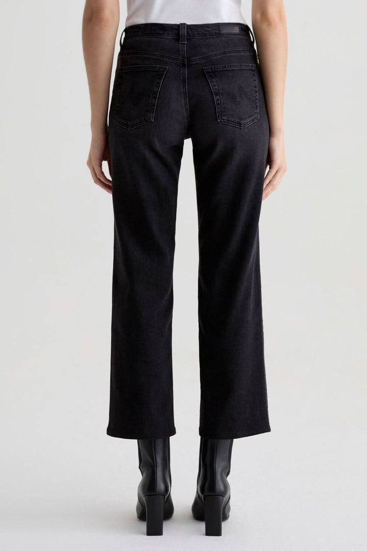 Personne portant un jean à coupe droite noir délavé avec des bottillons, vue arrière