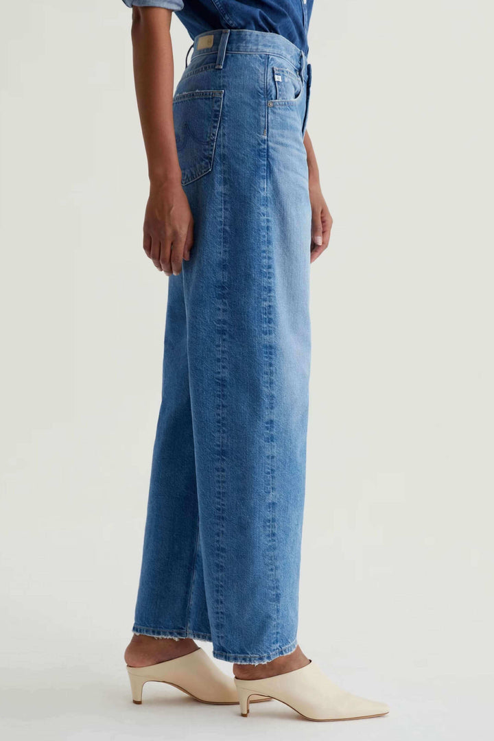 Jean droit à jambe large en denim bleu avec taille haute, vue latérale, style décontracté et moderne.