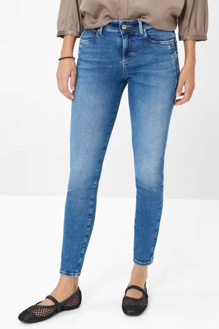 Jean skinny de style Ana, denim bleu clair légèrement délavé, coupe ajustée, taille mi-haute, look chic et décontracté.
