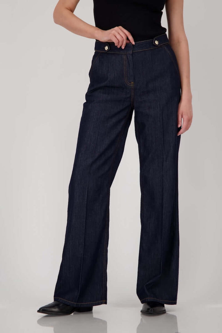 Jean taille haute en denim brut, coupe droite avec boutons métalliques et coutures visibles, longueur chevilles.