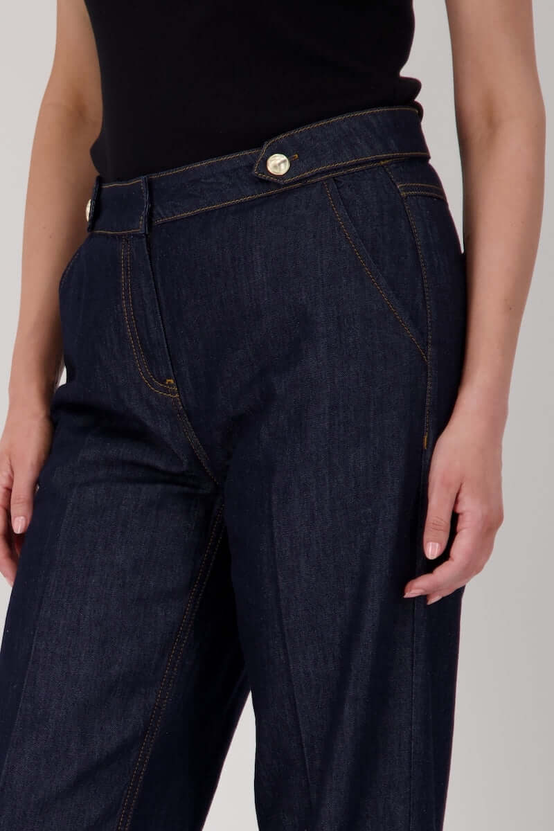 Jean taille haute en denim brut avec boutons métalliques et coutures visibles, coupe droite et ample jusqu&
