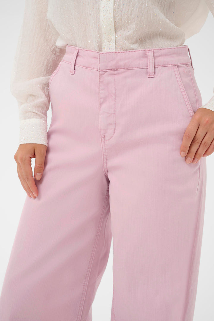 Jeans Visti à jambe large rose, taille régulière, porté avec une blouse blanche, mode moderne et élégante.