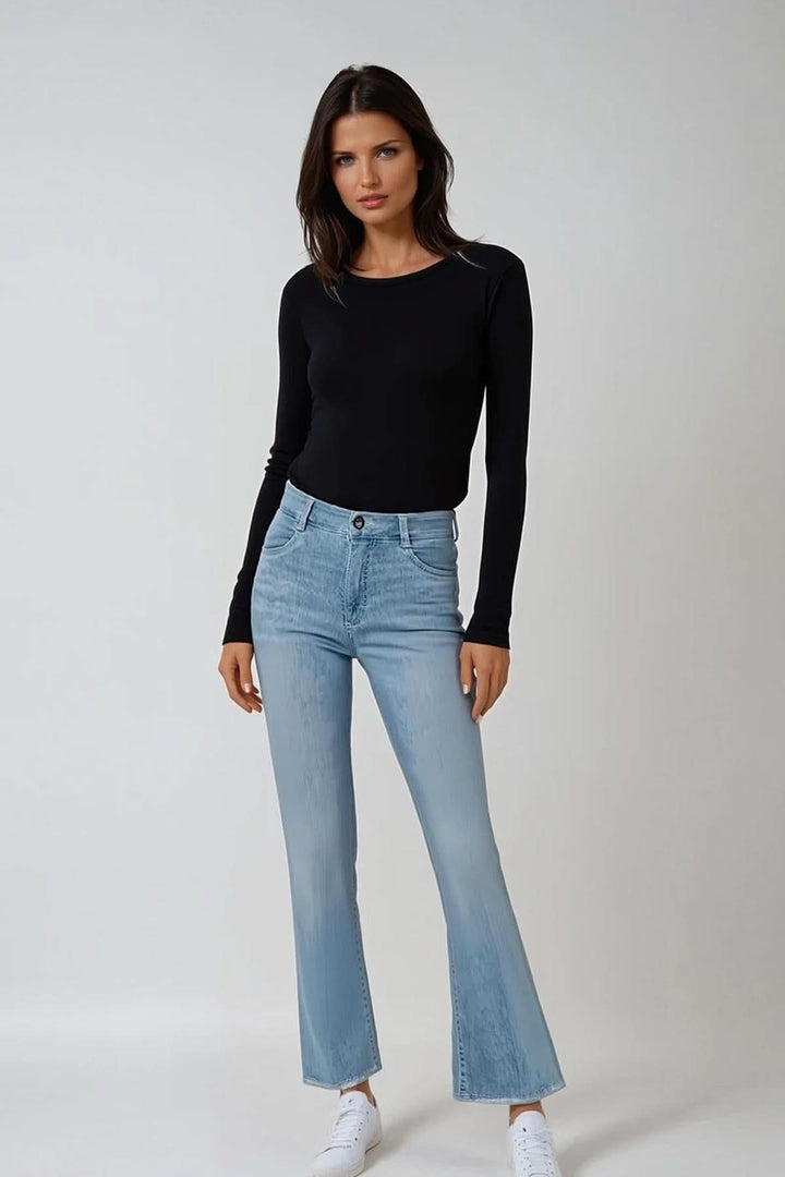 Femme portant le jean bootcut SHAKIRA S, haut noir, baskets blanches, style moderne et confortable.