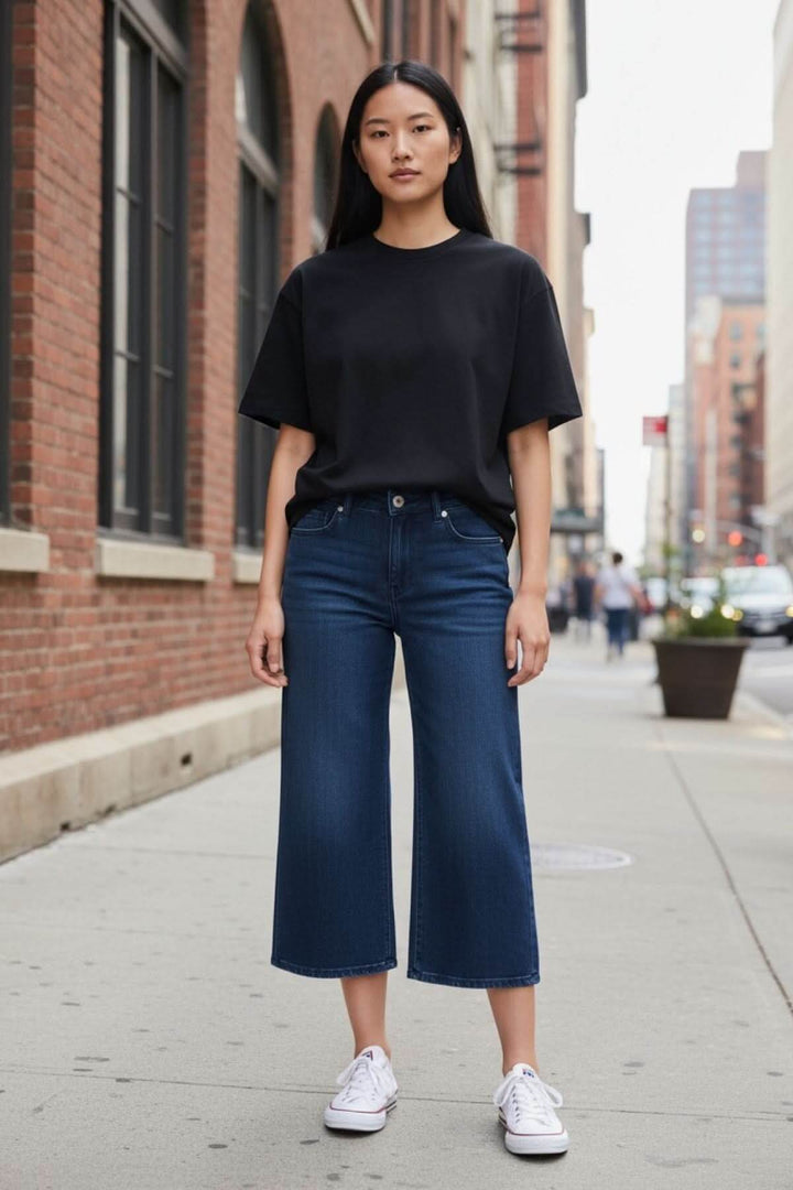Jeans jambe évasée avec coupe décontractée et taille régulière, porté par une femme en t-shirt noir dans la rue.
