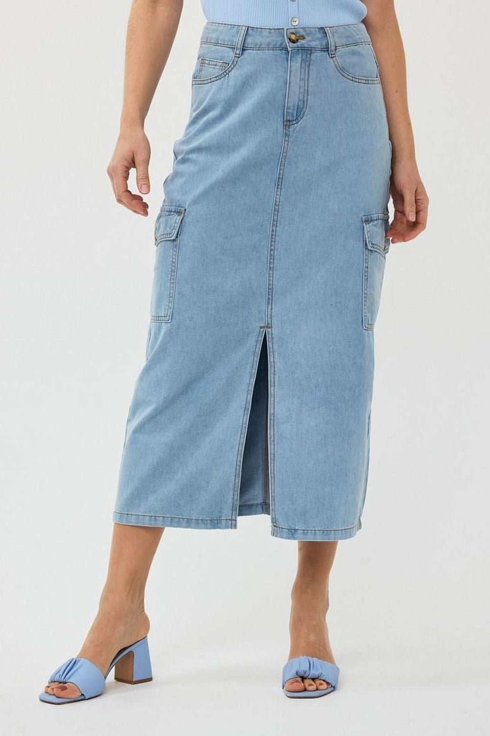 Jupe cargo en denim midi avec poches latérales et fente avant, portée avec des sandales bleues.