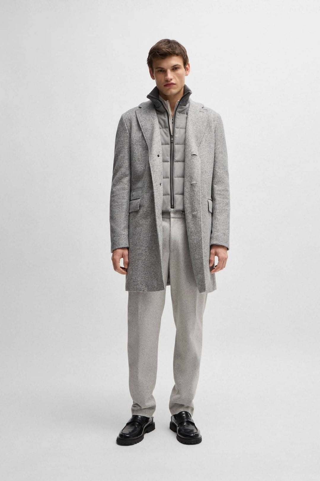 Homme portant un manteau à chevrons gris avec une fermeture amovible et un gilet intérieur gris.