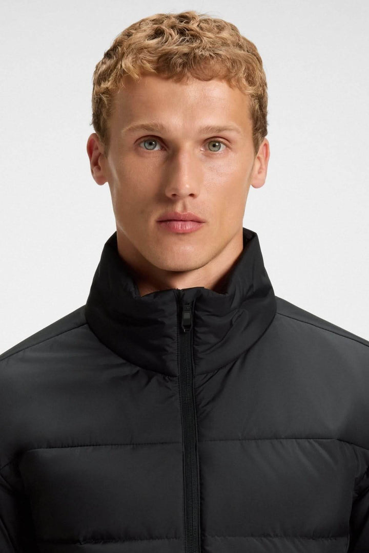 Homme portant un manteau matelassé déperlant en duvet avec poche sur la manche, style élégant et sportif.