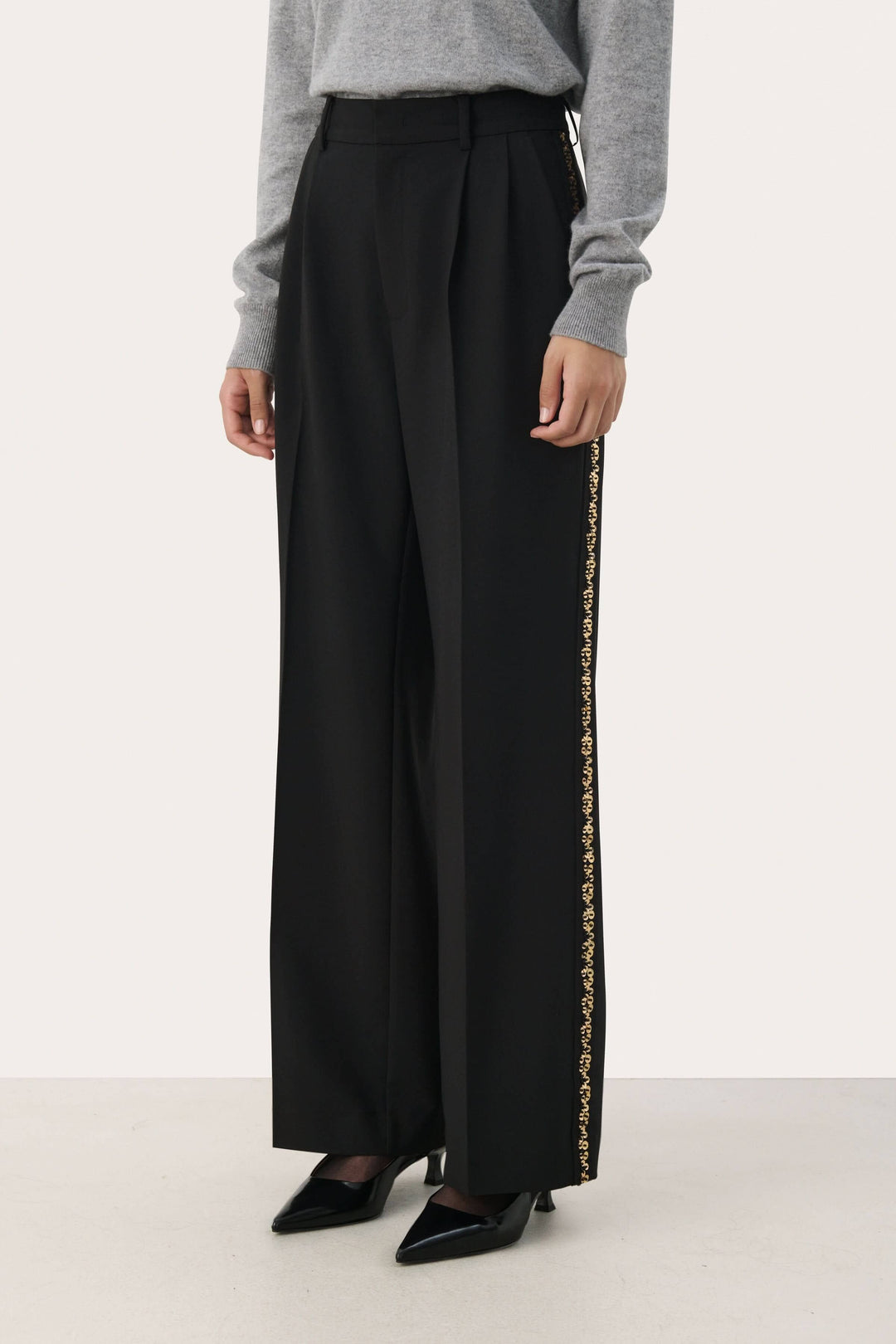 Pantalon noir large avec bande brodée dorée sur les côtés, taille haute, élégant et confortable.