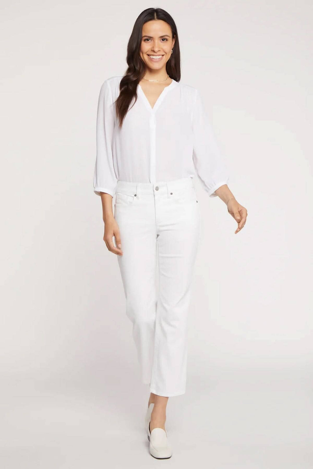 Femme portant un pantalon Marilyn blanc avec un haut en blanc, dégageant une allure élégante et classique.