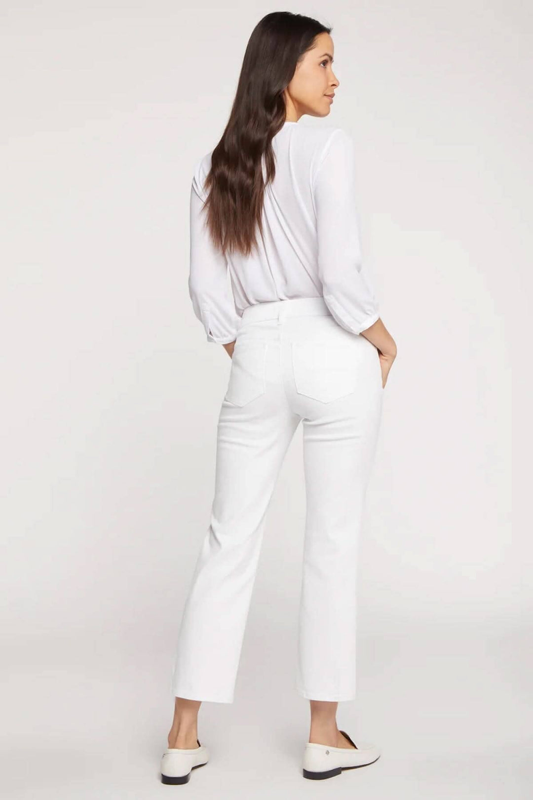 Femme portant le pantalon Marilyn, coupe classique blanche, silhouette droite atteignant la cheville, vue arrière.