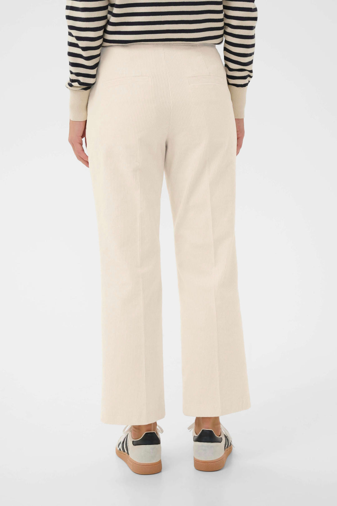 Pantalon Mishas en velours côtelé beige, coupe droite, taille mi-haute, longueur cheville, porté avec un chandail rayé pour un look chic.